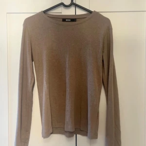 Beige långärmad tröja från Bik Bok - Säljer en enkel och stilren beige långärmad tröja från Bik Bok. Perfekt för höst och vår, den är gjord av mjukt och bekvämt material. Tröjan har en normal passform och är superlätt att matcha med olika outfits. Köp den nu och uppgradera din garderob! 💛