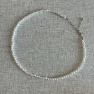 Ett fint vitt pärlhalsband som går att justera i storleken. Längsta längd är 57 cm och kortaste är 48 cm! I fint skick 💛