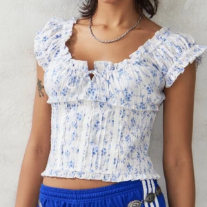 Blå topp - Så gullig blommig topp från Urban Outfitters. Har bara använts en gång. Nyskick. Perfekt för sommaren!! Köptes för 480kr!