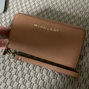 Michael Kors plånbok i använt skick, därav priset. Rymmer mycket och är även fin som en clutch. Jag brukar ha mobilen där i med. 