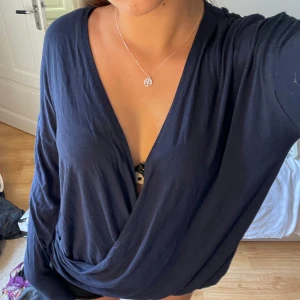 Omlottopp med spetsdetaljer - Mörkblå långärmad omlottopp med spetspartier i ryggen. Går att använde bakochfram (skriv för bild). Osäker på exakt storlek men passar allt ifrån xs-m.