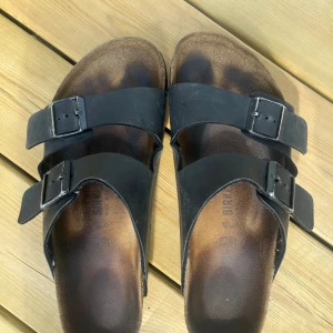 Birkenstock - De är ett par fina sandaler som använts 2 somrar, de är i okej skick och den lite mörkare svarta färgen är vatten sen jag tvätta av dem. De köptes på zalando för 1200kr i storlek 43