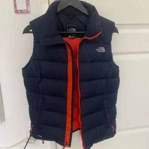 The north face vest -  Bra skick och inga defekter hittade. As cool Mörkblå/marinblå på utsidan och orange på insidan. Det står för women men tidigare ägaren var en kille, passar båda alla bra. kontakta för mer bilder. Äkta såklart!