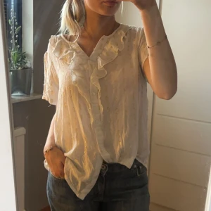 Blus - Super fin vit blus med volanger och guld detaljer. Passar perfekt när man ska vara finklädd. Står ingen storlek, men gissar att den är i storlek xs-s. Osäker på ifall jag ska sälja🩷