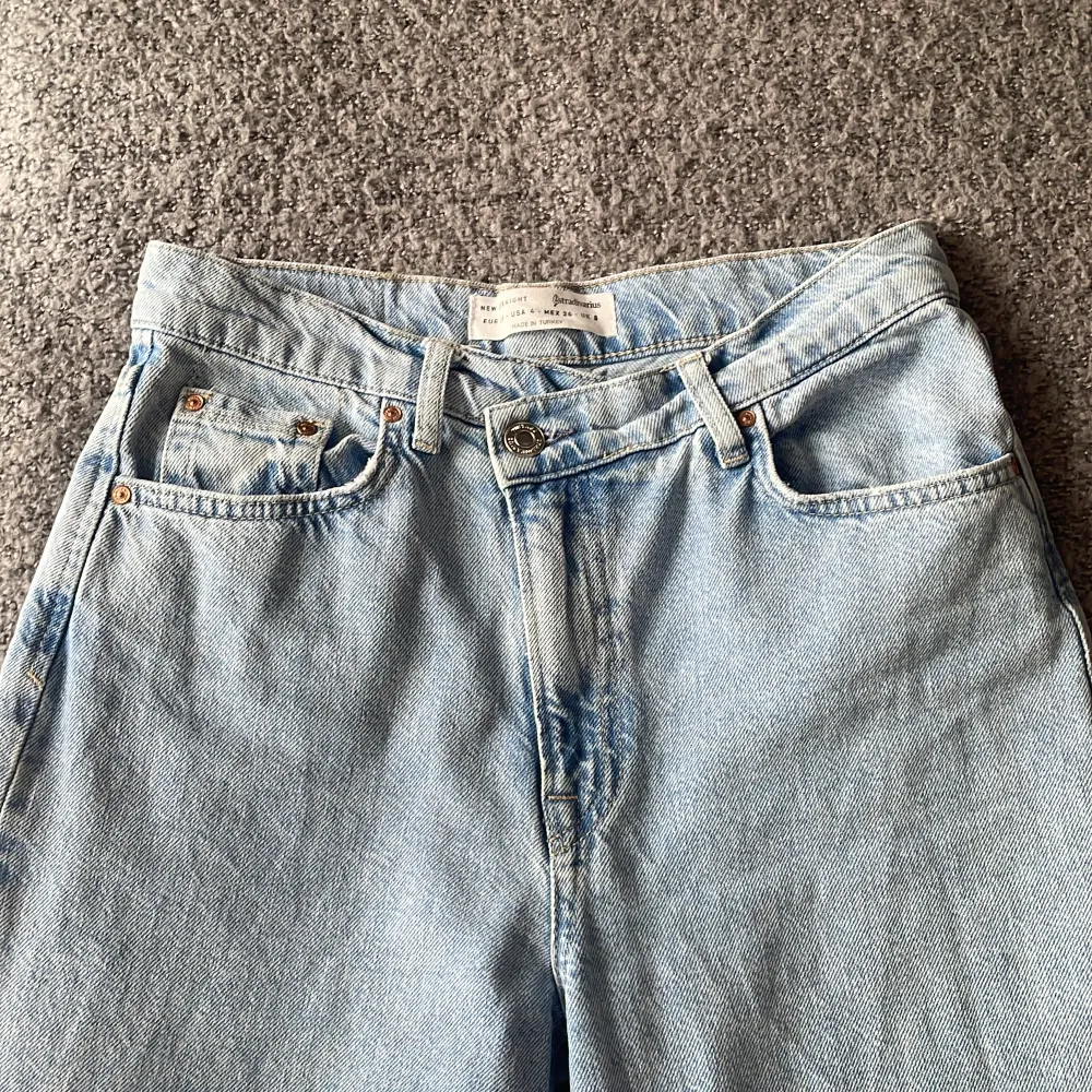 Snygga ljusblåa jeans, färgen mest lik på sista bilden. Där man knäpper byxorna är det en detalj där man knäpper byxorna snett nedåt. Byxorna är raka i modellen. Byxorna är otroligt snygga men kommer inte till användning! Köparen står för frakten!. Jeans & Byxor.