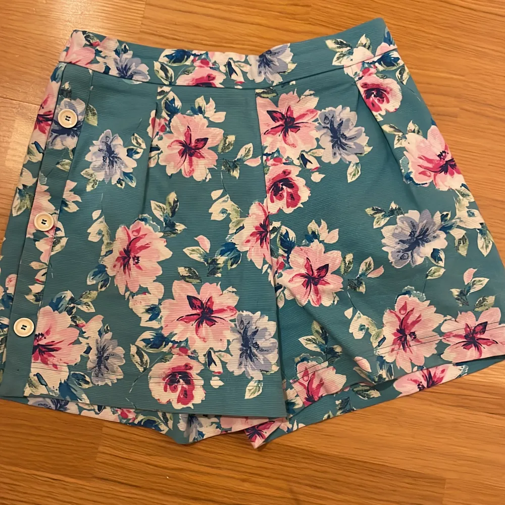 Väldigt bra skick på dessa blå blommiga shorts med knappar på sidan stl 164 och är från Zara aldrig använda där av priset💓. Shorts.