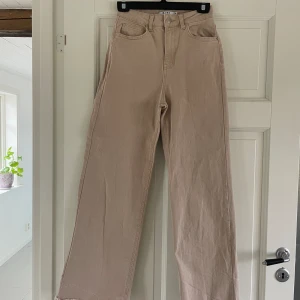 Beige jeans - Breda högmidjade beigea jeans från NA-KD. De är i ett mjukt jeans material och väldigt stretchiga, passar mig som är storlek 36. De är avklippta nertill så att de är kortare än originalet, jag är (167cm). Skriv privat för exakta mått. 
