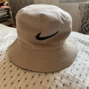 Nike solhatt - Nike solhatt som man kan välja om man vill ha svart eller beige. Man vänder den ut och in. Aldrig använd.