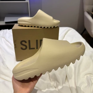 Yeezy slide bone - Säljer nu ett par helt oanvända yeezy slides ”bone”  Box medföljer, prislapp, adidas boxen, köpte från adidas confirmed men passade inte   Storlek 44,5 vid snabb affär kan priset diskuteras