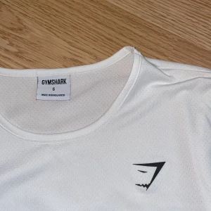 Vit Långärmad Gym Shark Träningströja  - Säljer min träningströja från Gymshark!  Fint skick, då den aldrig kommit till andvändning! OBS : Den kan vara lite genomskinlig! Kontakta gärna vid frågor eller fler bilder☺️! 