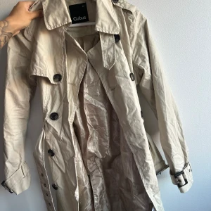 Trenchcoat - Oanvänd trenchcoat från Cubus storlek 34. Passar xs/s Aldrig använd med skulle behöva strykas 