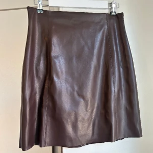 Mörkbrun kjol i läderimitation  - Mörkbrun kjol i läderimitation, Lindex  (Sista bilden visar kjolen i svart)  PU material yttre, polyester 96, elastane 4% linningen   Så snygg, men säljer pga för stor tyvärr.  Skick: använt skick men fräsch, inga skavanker
