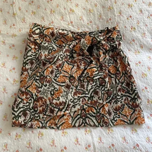 Zara kort kjol mönstrig  - Aldrig använd, lappen kvar. Knyts ihop på framsidan. Liten i storleken, storlek L men skulle säga att den är en M. Rätt kort ☺️