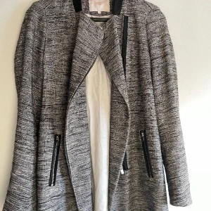 Vårkappa märke Maje - Storlek 38. Längd 80cm. Svart och vit. Fickor med blixtlås 