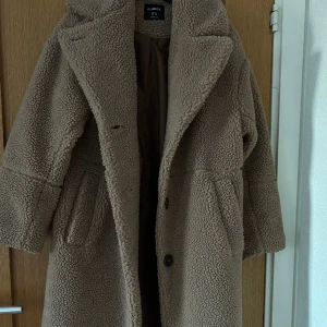 Brun Teddykappa - Brun Teddykappa från Lindex oversized modell. Kappan är i storlek XS men oversized 🐻. Använd endast en gång och säljer pågrund av att jag inte får användning av den💖