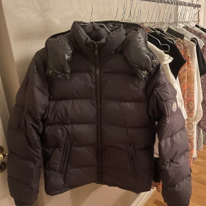 Brun Moncler Chevalier - Säljer min superfina bruna Moncler Chevalier då det tyvärr inte kommer till användning längre. Äktehetsbeviset syns i qr koden i jackan. Jackan är i bra skick men har en bytt dragkedja och lappen på insidan är lite lös men går lätt att fixa