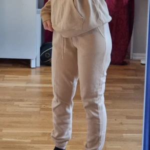 Beige set med huvtröja och mjukisbyxor - Säljer mitt beige mjukisset som inte kommer till använding, helt oanvända och i nyskick