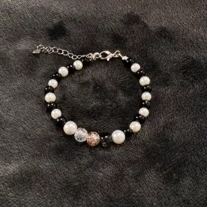 Handgjort pärlarmband med svart-vita pärlor och krackelerade pärlor i mitten och silvrigt spänne. Justerbar passform mellan 19-25 cm.💕