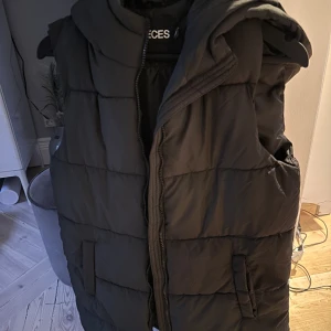 Svart dunväst  - Längre dunväst från Pieces, aldrig använd men lapparna är borta. Med luva!  