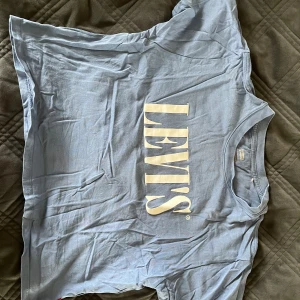 Blå levis T-shirt  - Blå levis T-shirt i fint skick, använd en sommar. Den är kort i modell och slutar i höjd med naveln. Säljer då den är för liten för mig. 