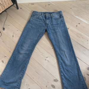 Ett par mellan/ljusblå Levis jeans i modellen 527 storlek 32/32. De har blivit avklippta av tidigare ägare så längden stämmer inte överens. De har även en liten fläck på vänstra benet lite längre ner men är inget man tänker på när man har på sig dem.