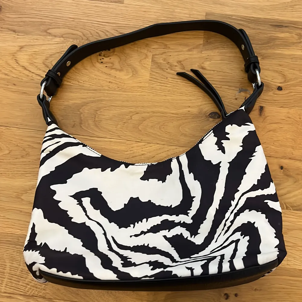 Don Donna väska i perfekt skick. Använd fåtal gånger. Inga defekter. Finns kort band och ett längre band. Typ zebra print . Accessoarer.