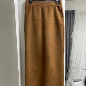 Långkjol - läderimitation - Långkjol, i läder material. Verkligen fin och skön. Den är lite stretchig av sig, ser elegant ut. Köpt för 199kr säljer för 100kr. Färgen är ljusbrun.