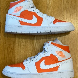 Jordan 1 mid bright citrus 39 - Storlek 39  Orange vita sneakers med reflex snören.  Inte använda mycket.  Använda med creaseskydd då de har använts 