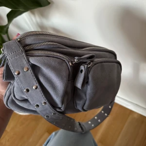 Blå gina tricot väska - Supersnygg gina tricot väska som inte längre säljs! Sparsamt använd. Matt sammetliknande materiel. Väskan har många fack. 