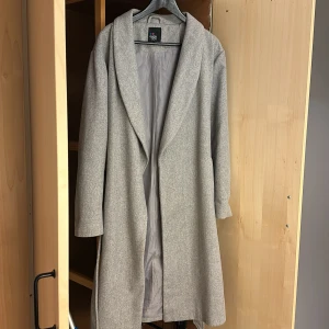 Grå medelång kappa - Säljer denna fina och eleganta kappan från märket even & odd. Den är i väldigt bra material och man håller sig varm. Passar perfekt nu till vår eller höst. Är mer åt de oversized hållet och sitter avslappnat på kroppen vilket formar en fint🥰 