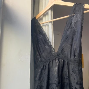 Svart silkesklänning med spets - Superfin maxi/miniklänning med blommigt silkestyg och spets. Går att ha åt båda hållen, djup i rygg med knytdetalj.  S/M Jag är 160cm