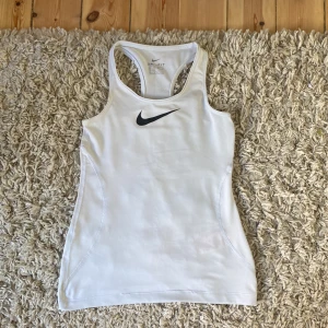 Nike träningslinne - Jätte snyggt vitt Nike linne! Säljer detta träningslinne då det har blivit för litet.  Har nästan aldrig använt detta linnet. Linnet är väldigt stretchigt vilket gör att storleken på linnet kan passa ändå.