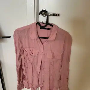 Rosa skjorta med 2 fickor på brösten.   Endast använd 2-3 gånger.