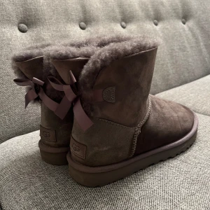 Ugg-vinterstövlar  - Ugg mini bailey bow grå. Storlek 39. Använd några gånger, i bra skick. Original pris 2195 kr