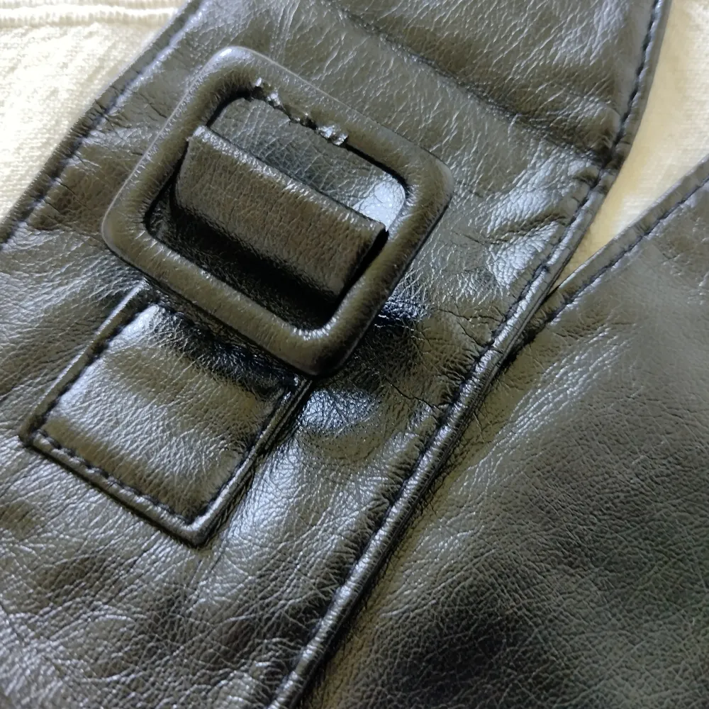Svart brett skärp/bälte/midjeskärp i fake leather som man passar många då man kan justera längden. Ett par små märken i 