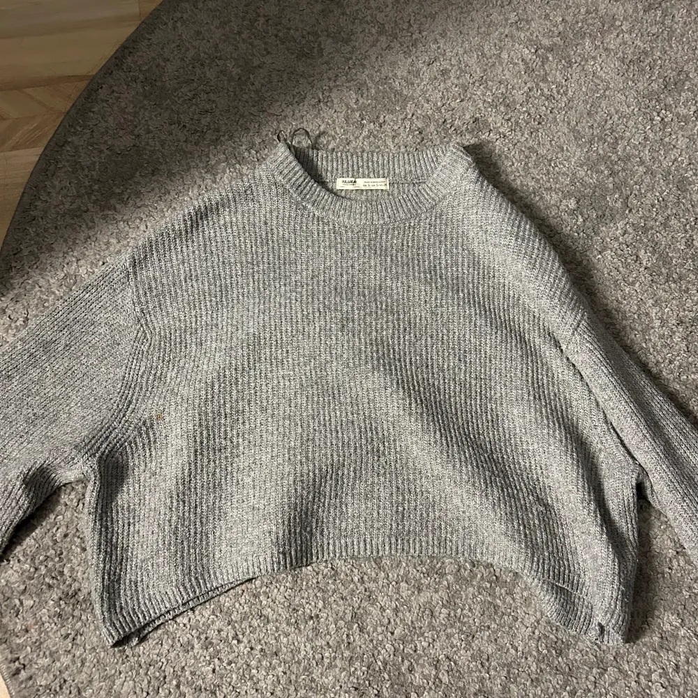 Säljer denna gråa fina stickade tröja från Pull&Bear då den tyvärr inte kommer till användning. Skulle säga att den är lite kortare(magtröja) Säljer för 200kr då det finns en liten fläck🩶. Stickat.