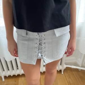 Grå kjol med snörning och ”fake” fickor