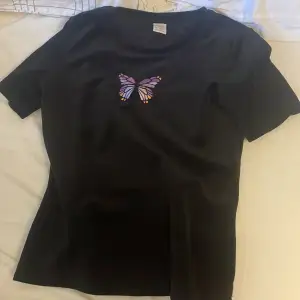 Hej! Nu säljer jag min svarta sammet t-shirt med en lila fjäril på från Lindex.  Använd fåtal gånger. Storlek: 146/152. Nypris: ca 150kr. Mitt pris: 80kr. Köparen betalar frakten. 