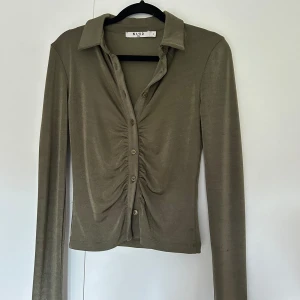 Grön topp med knappar - Långärmad grön topp med rynkor och knappar. Använd en gång