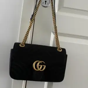 Gucci inspirerad väska i modellen GG Marmont Flap velvet crossbody bag Black, Velvet.  Den är prydd med märkets ikoniska GG-signatur som verkligen sticker ut mot det skarpa svarta velvet. Sparsamt använd. Mått 26 x 14 x 7 cm. Se gärna mina andra anno