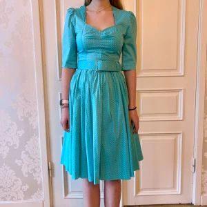 Prickig klänning med skärp, Emmy design  - Jättefin blå och vit prickig klänning i skönt material. Storlek 38. Kommer med skärp. Modellen på bilden är 173 cm och har storlek 38 i de flesta andra kläder. Aldrig använd. Vi har lagt ner vår klänningsbutik och säljer ut. Ny pris är 2000-3000kr