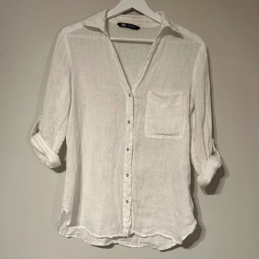 En vit linneskjorta från Zara i storlek XS. Skjortan har guldfärgade knappar, en ficka framtill och knappar på ärmarna så de både kan rullas upp eller inte. Skjortan har knappt använts och är i ett mycket bra skick.. Skjortor.