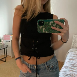 Topp med snörning  - Svart topp med snörning/korsett. Går att reglera hur tajt man vill ha den