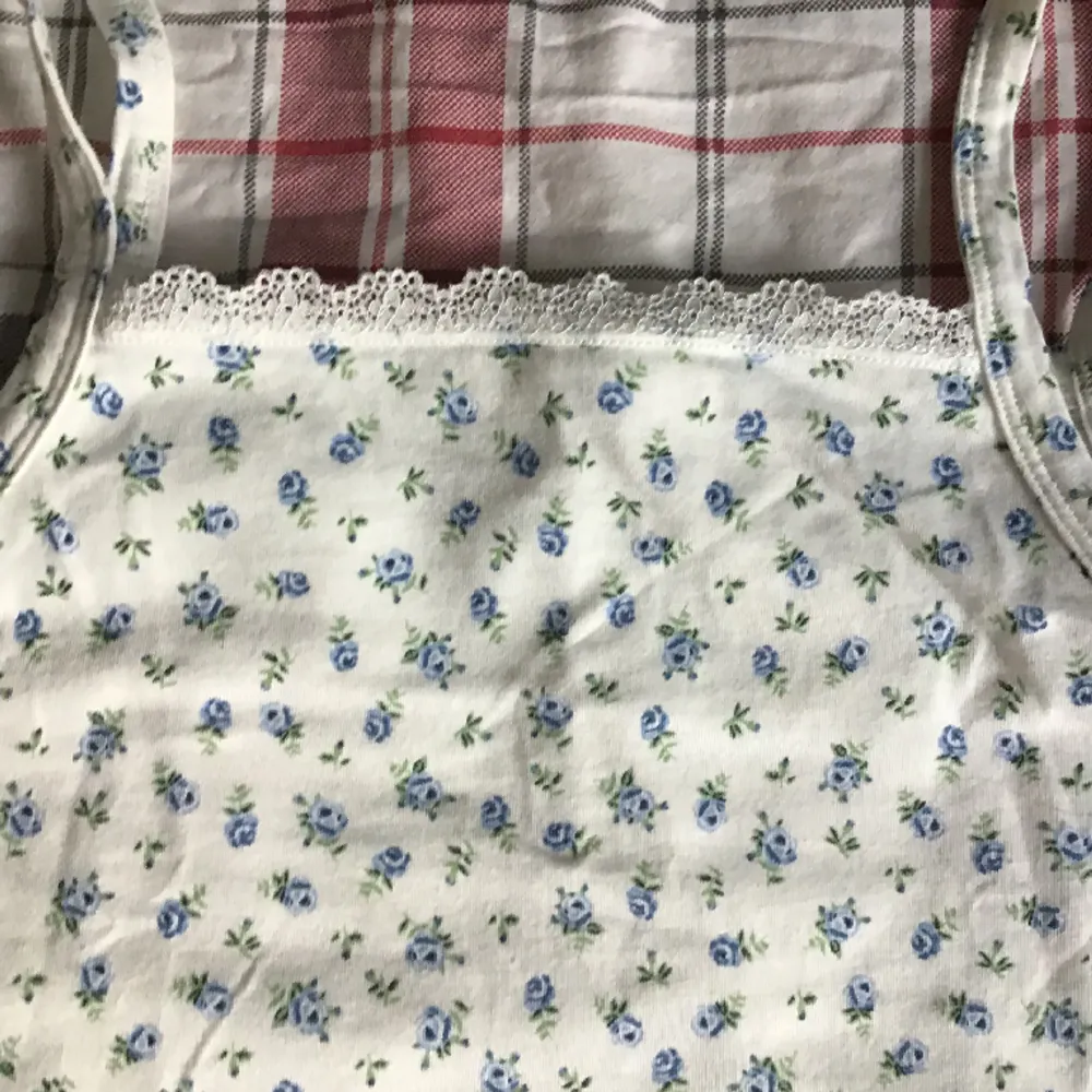 En blommig blå vit spets linne from H&M Kids men passar som ett XS, har använts väldigt få gånger.. Toppar.