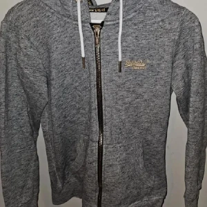 Superdry hoodie - Hoodie från märket superdry. Begagnat skick men inga specifika defekter (endast naturligt slitage). Tjockt material så passar perfekt i kylan!