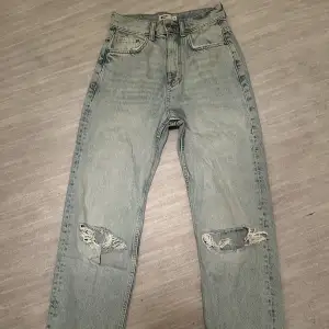 Högmidjade jeans från Gina Tricot med hål. Ej använda. Storlek 32. Köparen står för frakten.