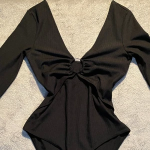Body med silverdetalj - Svart body med djup V ringning och en silver ring, Tycker den ger lite taylor swift vibes men den är tyvärr för stor för mig. Storlek s 