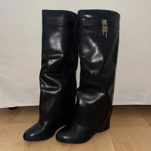 Knähöga svarta stövlar i fuskläder med hänglås detalj från EGO. Är en perfekt Givenchy shark boots dupe. Endast testade en gång innomhus, säljer pga liten storlek.