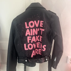 Skinnjacka med text!! - En jättefin skinnjacka som jag köpte av en tjej som designa eget för något år sedan!! Jackan är i storlek Medium men skulle säga att den sitter mer som Small!! Pris går att diskuteras , hör av dig vid mer frågor 🙌🏼🩷