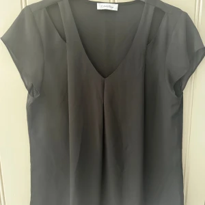 Kortärmad blus Calvin Klein stl 38/40 - Kortärmad svart blus Calvin Klein stl 38/40  100:- Mycket fint skick. Djur- och rökfritt hem.